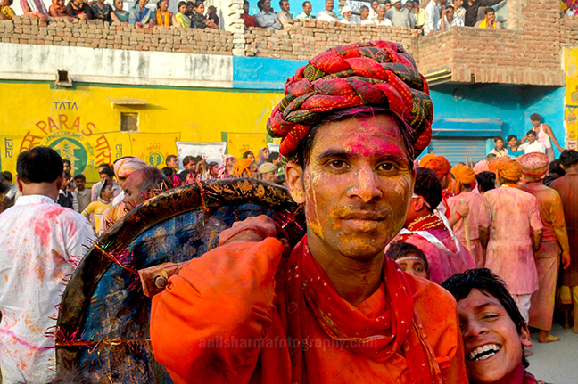 Festivals- Lathmaar Holi of Barsana (India) - A man daubed in color powder smiles as he celebrates lathmaar Holi at Barsana, Mathura, India. by Anil Sharma Photography