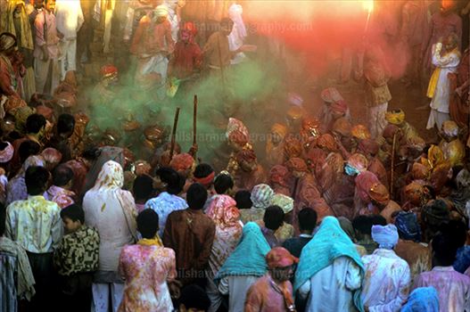 Large number of people gathered sprinkle colored powder, singing, dancing during Lathmaar Holi celebration at Barsana, Mathura, India.